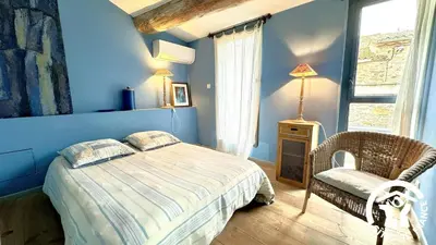 a bedroom with a bed and a chair and a window at Gîte Brassens in Pouzols-Minervois
