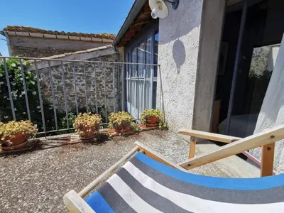 a balcony of a house with a chair and potted plants at Gîte Brassens in Pouzols-Minervois