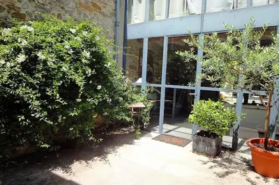 a building with plants and a bench in front of it at Gîte Brassens in Pouzols-Minervois