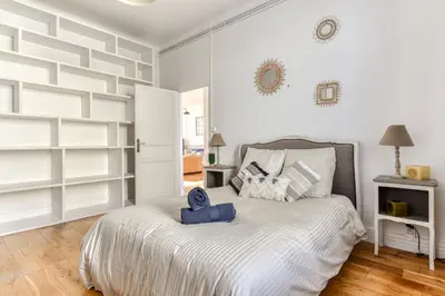 a bedroom with a large bed with white walls at Big House - Parking Privée - Piscine - Wifi - tout équipée in Carcassonne