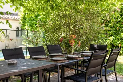a wooden table with chairs and plates on it at Big House - Parking Privée - Piscine - Wifi - tout équipée in Carcassonne