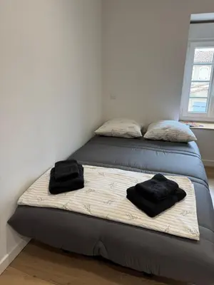 a bed with two black pillows on top of it at La perle limouxine -Studio in Limoux