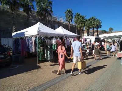 a man and a woman walking past a street market at Studio 3 pers à Gruissan - Vue Port - Parking - Climatisation Mobile - FR-1-796-89 in Gruissan