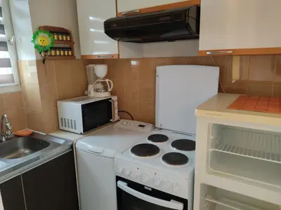 a small kitchen with a stove and a microwave at Studio 3 pers à Gruissan - Vue Port - Parking - Climatisation Mobile - FR-1-796-89 in Gruissan