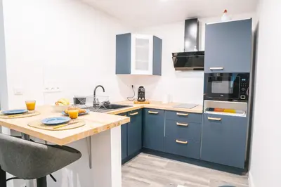a kitchen with blue cabinets and a wooden table at Face à la cité, Terrasse Et Climatisation - AE in Carcassonne