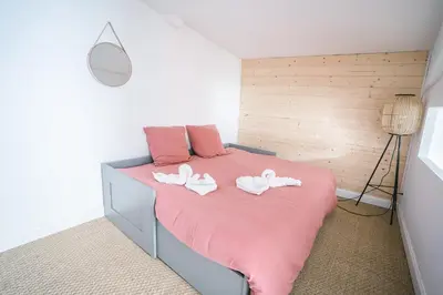 a bedroom with a pink bed with two white towels at Face à la cité, Terrasse Et Climatisation - AE in Carcassonne