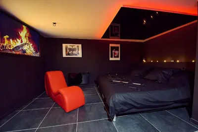 a bedroom with a bed and a red chair at Love room évasion in Tuchan