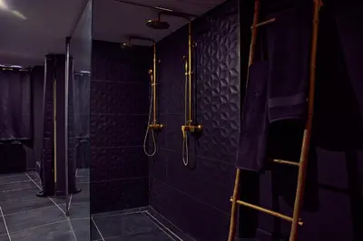 a bathroom with a shower with black tiles at Love room évasion in Tuchan