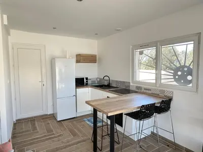a kitchen with a white refrigerator and a wooden table at Rubis in Lapalme