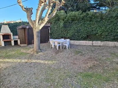 a table and chairs under a tree in a yard at Appartement Salles d 'Aude in Salles-d'Aude