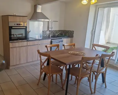 a kitchen with a wooden table and chairs in a kitchen at La Villa Cécile in Saint-Martin-de-Villereglan