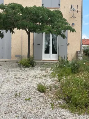 a tree in front of a house with a door at Entre Mer et Vigne Caves in Caves