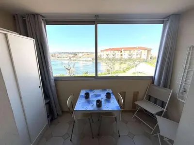 a table and chairs in a room with a large window at Appartement Studio-Cabine PORT-LA NOUVELLE PN290-074 in Port-la-Nouvelle