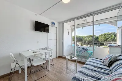 a living room with a couch and a table with chairs at Le Cordier - Apartment near the harbor in Gruissan