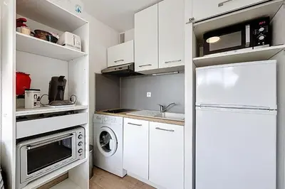 a kitchen with white cabinets and a white refrigerator at Le Cordier - Apartment near the harbor in Gruissan
