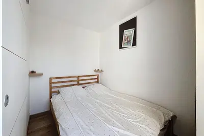 a small white bedroom with a bed in it at Le Cordier - Apartment near the harbor in Gruissan