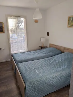 a bedroom with a bed with a blue comforter and a window at Escapade à Nailloux in Nailloux