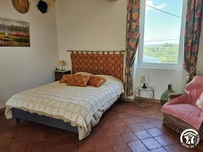 a bedroom with a bed and a window and a chair at La surprise des jumelles in Castres
