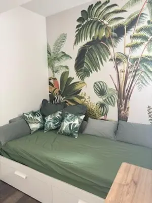a green couch in a room with a mural of palm trees at Studio design hypercentre Gare & espresso offert in Castelnaudary