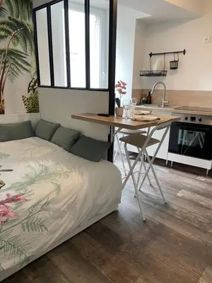 a bedroom with a bed and a table and a kitchen at Studio design hypercentre Gare & espresso offert in Castelnaudary