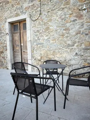 two chairs and a table in front of a stone wall at Au cocon des corbières - Élégance in Lézignan-Corbières