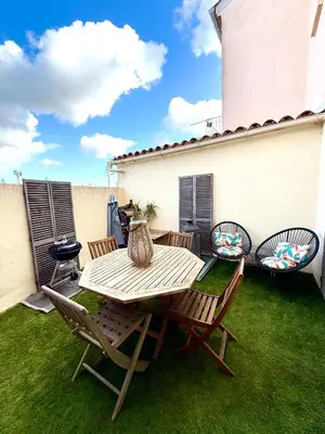 a patio with a table and chairs on the grass at Appartement Narbonne centre in Narbonne