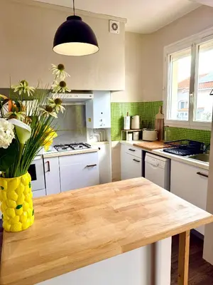 a kitchen with a wooden table with a vase of flowers at Appartement Narbonne centre in Narbonne