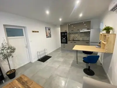 a kitchen with a table and a blue chair at Gîte la Cave in Quarante