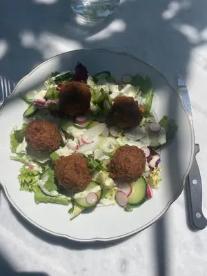 a plate of food with meatballs on a salad at Les volets verts in Saint-Laurent-de-la-Cabrerisse