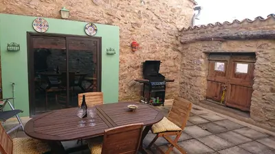 a wooden table and chairs on a patio with a wood stove at Avalon in Caunes-Minervois