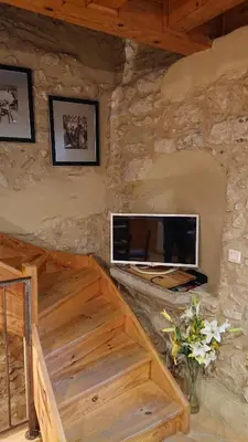 a living room with a television on a stone wall at Avalon in Caunes-Minervois