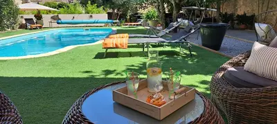 a table with a drink on it next to a pool at Le MAS CLEMENTINE in Puisserguier