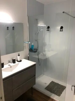 a white bathroom with a sink and a shower at APPARTEMENT F3 BOX Vélo Moto Centre historique in Mirepoix