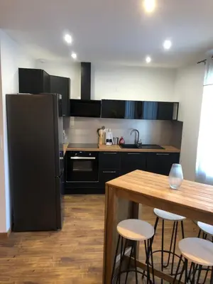 a kitchen with a black refrigerator and a wooden table at APPARTEMENT F3 BOX Vélo Moto Centre historique in Mirepoix