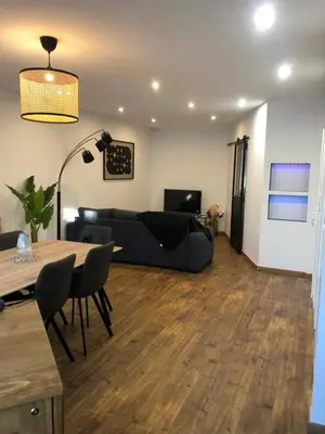 a living room with a black couch and a table at APPARTEMENT F3 BOX Vélo Moto Centre historique in Mirepoix