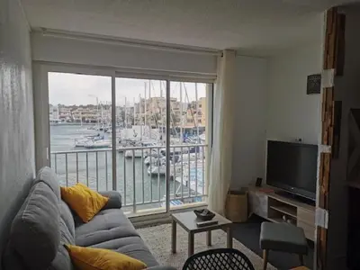 a living room with a couch and a large window at Studio Cabine Vue Port Gruissan in Gruissan
