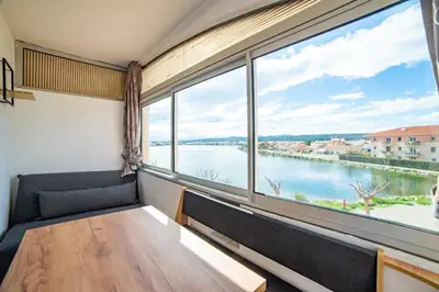 a room with a large window overlooking the water at Vue lac & mer à pied - Séjour détente in Port-la-Nouvelle