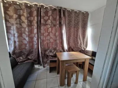 a room with a table and a couch and curtains at Vue lac & mer à pied - Séjour détente in Port-la-Nouvelle