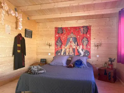 a bedroom with a bed with a tapestry on the wall at HARRY POTTER-Chalet du Sanglier Magique - in Boutenac