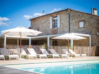 a group of chairs and umbrellas next to a pool at Domaine de Vadel in Veilhes