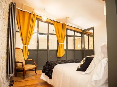 a bedroom with yellow curtains and a bed and a chair at Domaine de Vadel in Veilhes