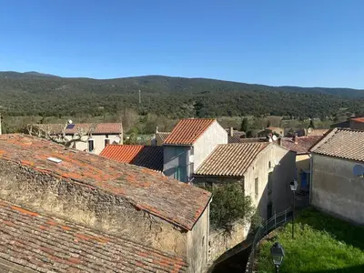 a view of a town with roofs and mountains at Gîte lumineux avec jardin, vue sur Peyrepertuse in Rouffiac-des-Corbières