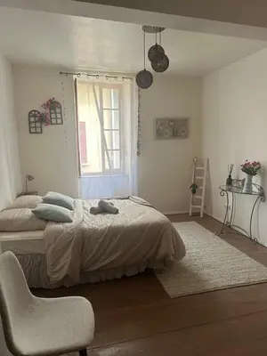 a bedroom with a bed and a chair and a window at Maison de charme à Bélesta in Bélesta