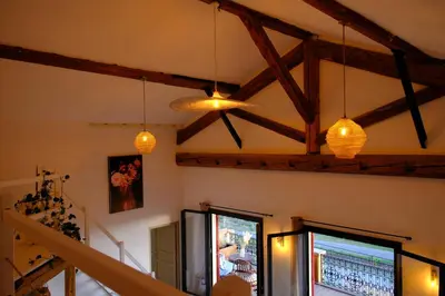 a living room with wooden beams and pendant lights at Maison de charme et vue Imprenable à 180 degrés sur les vignes et Pyrénées in Paraza