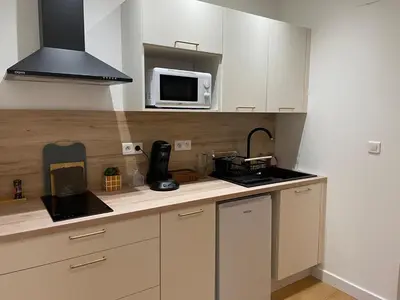 a kitchen with white cabinets and a microwave at Stylish Apartment with Balcony - Very Central - Long Stays and Pets Welcome in Carcassonne