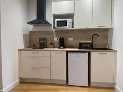 a kitchen with white cabinets and a microwave at Stylish Apartment with Balcony - Very Central - Long Stays and Pets Welcome in Carcassonne