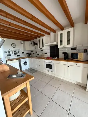 a large kitchen with white cabinets and white appliances at Gîte au cœur d un caveau de dégustation de vin in Olonzac