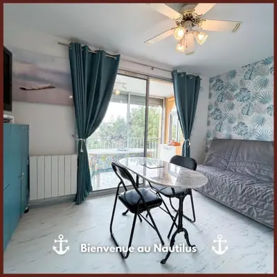 a bedroom with a table and a bed and a window at Le Nautilus in Gruissan