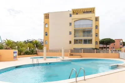 a swimming pool in front of a building at Le Nautilus in Gruissan