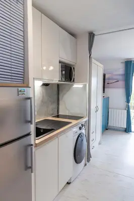 a white kitchen with a refrigerator and a dishwasher at Le Nautilus in Gruissan